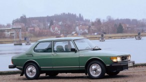 The side view of a green 1978 Saab 99 Turbo by a harbor