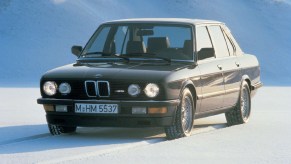 A black 1985 E28 BMW M5 on a snowy mountain