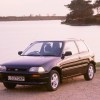 A dark-colored 1994 Daihatsu Charade GTI hatchback parked by a lake