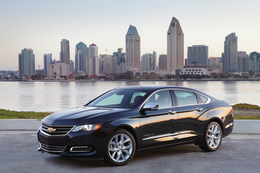 A black 2018 Chevy Impala parked in front of water and a cityscape