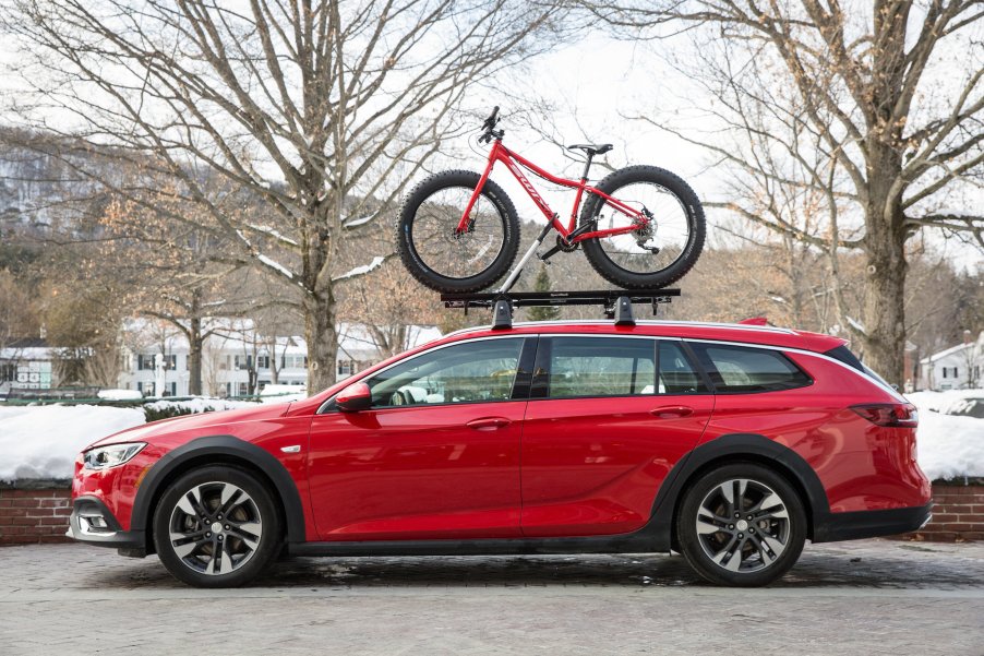 A red 2019 Buick Regal TourX carries a bicycle on its roof in Vermont during the winter