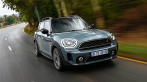 A blue 2020 Mini Countryman SUV cruises along a wooded road