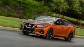 An orange 2020 Nissan Maxima driving down a country road