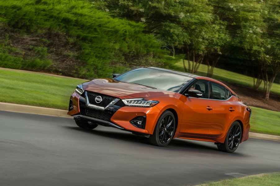 An orange 2020 Nissan Maxima driving down a country road