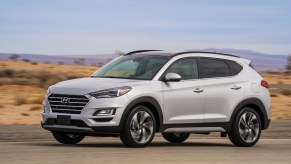 A silver 2021 Hyundai Tucson parked on display next to rugged terrain