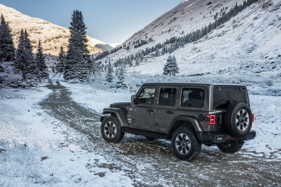 A grey 2021 Jeep Wrangler driving on a snowy road