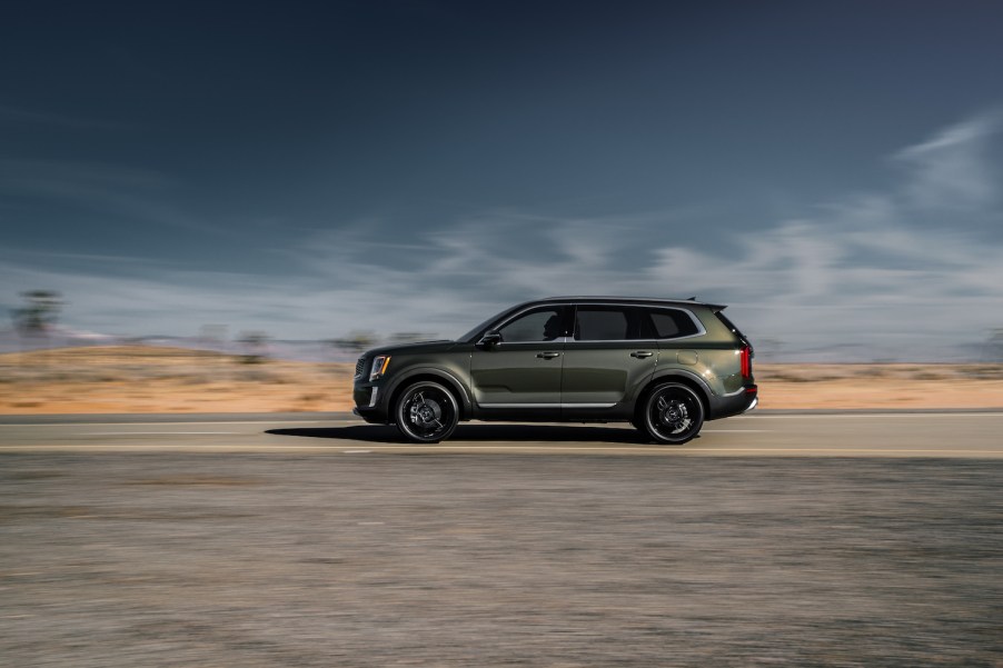 An olive green 2021 Kia Telluride driving down an empty road