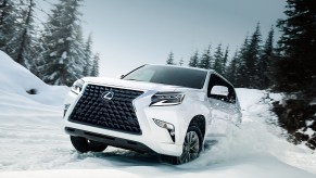 A white 2021 Lexus GX full-size SUV drives through the snow