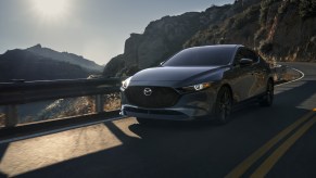 A grey 2021 Mazda3 Hatchback driving down a highway road