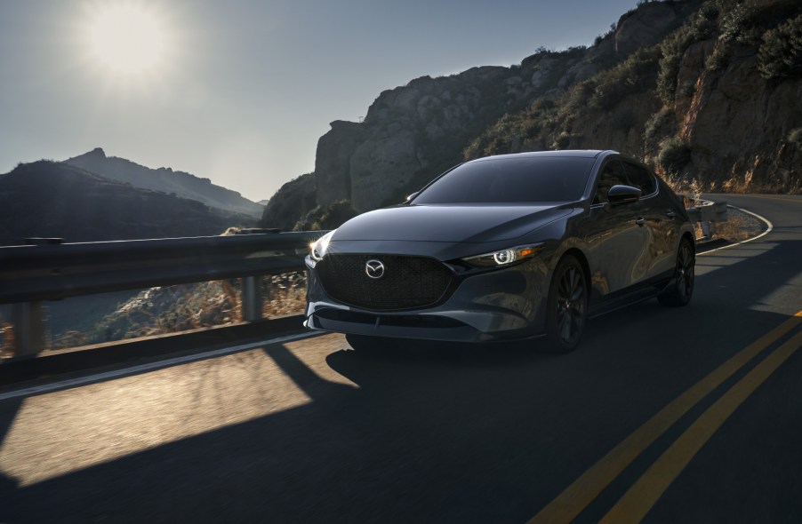 A grey 2021 Mazda3 Hatchback driving down a highway road