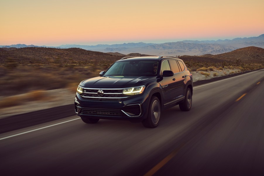 A black 2021 Volkswagen Atlas drives on a road with mountains in the background