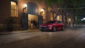 A red 2021 Chevy Malibu on display next to a building with lights on it