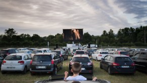 A boy sticks his head out of the sunroof of a car