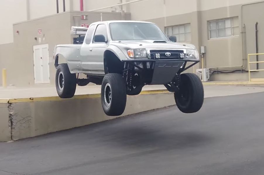 A Suxtom Silver Toyota Tacoma jumping off of an elevated loading dock.