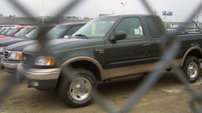 A row of Ford pickup trucks sits behind a gate