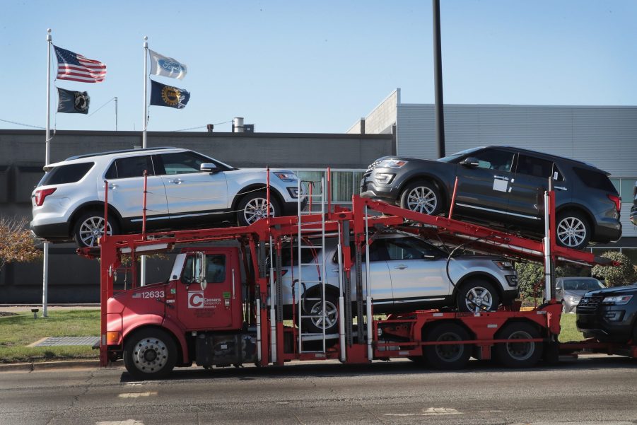 A truck carrying Ford SUVs to a car dealership