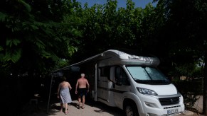 Two people walk outside an RV camper.