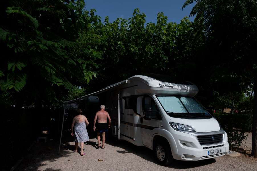 Two people walk outside an RV camper.