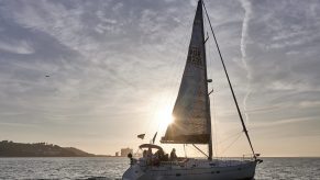 The sun sets behind a sailboat belonging to Escola de Navegação Treino de Mar (Navigation Training School of the Sea)