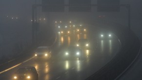 Cars' headlights can be seen through snow and fog on a highway