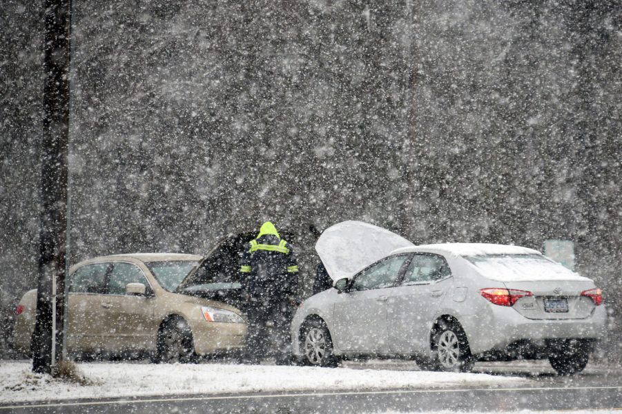 Two cars left straned in a winter storm as a man tries to help jump a car battery