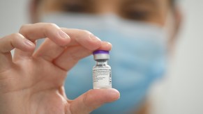 member of staff poses with a phial of Pfizer-BioNTech Covid-19 vaccine