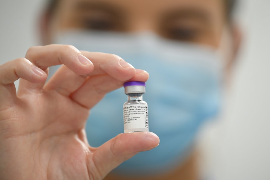 member of staff poses with a phial of Pfizer-BioNTech Covid-19 vaccine