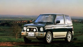 A dark-green 1994 Mitsubishi Pajero Mini on a grassy hill