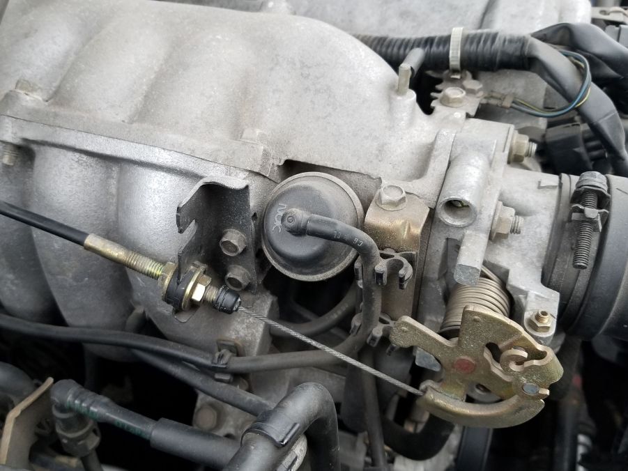 The intake manifold, throttle body, and throttle cable of a 1999 Mazda MX-5 Miata