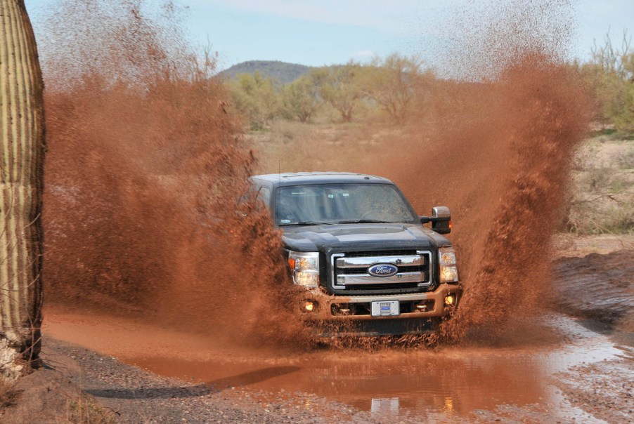 A black 2011 Ford F-250 Super Duty Power Stroke diesel pickup truck drives through mud