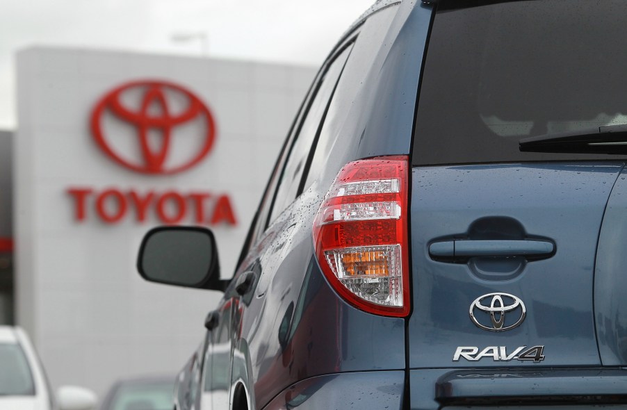 A look at the rear of a blue 2012 Toyota RAV4 with the red Toyota logo in the background