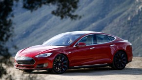 A red A 2015 Tesla Model parked on a dirt road in front of mountains in California S P85D