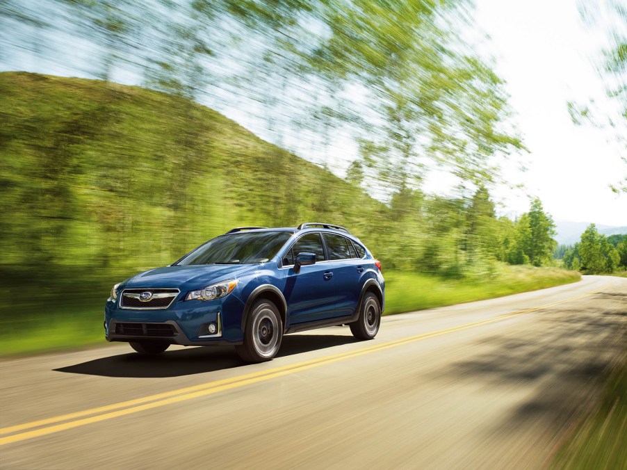 A blue 2016 Subaru Crosstrek driving down a highway road