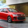 A red 2020 Chevy Sonic parked hatchback parked next to a modern gray house