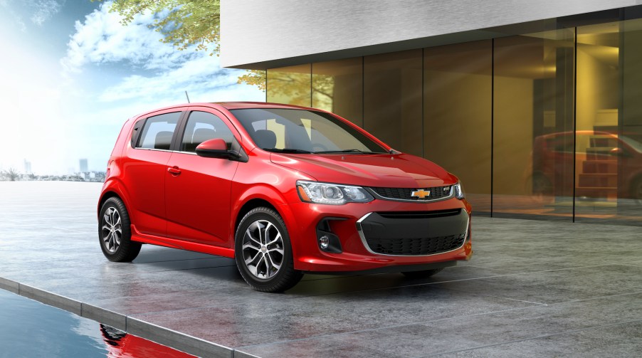 A red 2020 Chevy Sonic parked hatchback parked next to a modern gray house