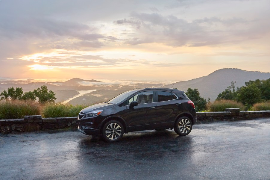 A dark-colored 2021 Buick Encore sits on wet pavement on a mountainside