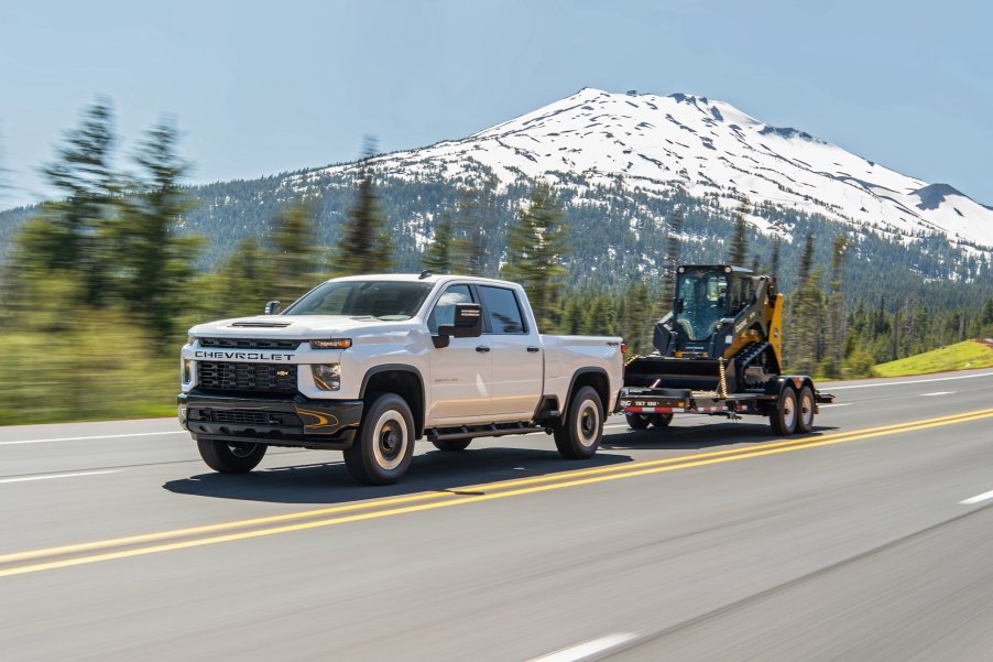 A white 2021 Silverado 2500 HD Custom tows a front-end loader