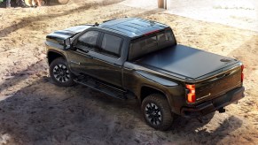 A black 2021 Chevy Silverado HD Carhartt Special Edition parked in the dirt next to a tractor