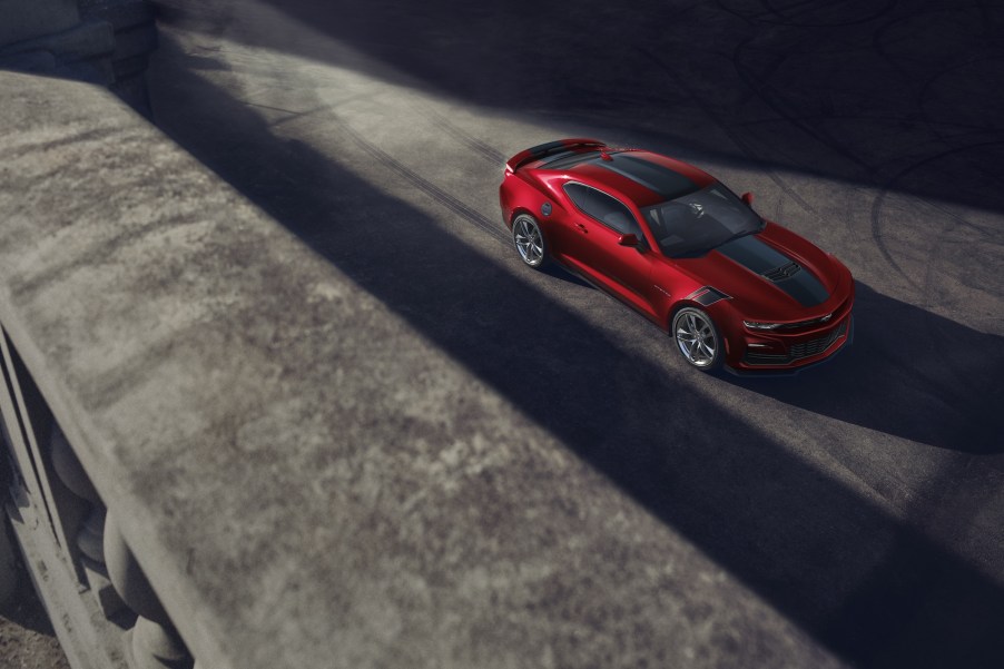 A dark-red 2021 Chevy Camaro SS with racing stripes sits on a bridge