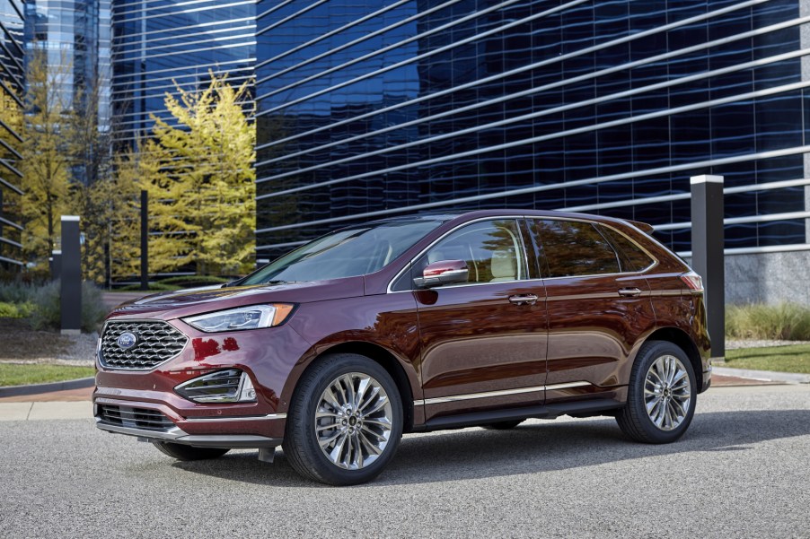 A dark red 2021 Ford Edge Titanium Elite parked in front of a tall building