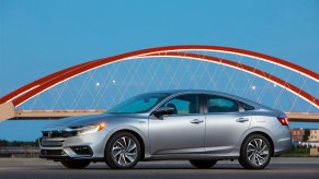 A silver 2021 Honda Insight hybrid sedan parked in front of a red bridge and blue sky