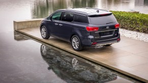 A dark-colored 2021 Kia Sedona parked next to water