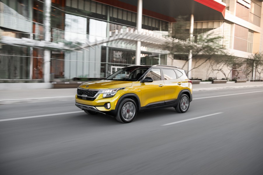 A gold 2021 Kia Seltos small SUV driving down a city road