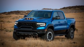 A metallic blue 2021 Ram 1500 TRX parked in a field of brown grass and weeds