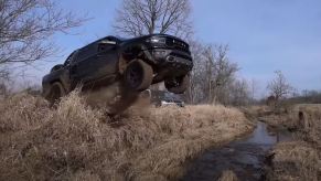 A black 2021 Ram 1500 TRX off-road pickup runs off the end of a ramp.