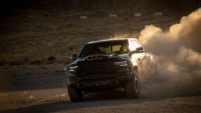 A black 2021 Ram 1500 TRX driving off-road with dirt kicking up