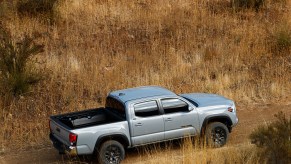 A silver 2021 Toyota Tacoma Trail Edition parked on a dirt road amid brown weeds