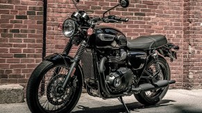 A black 2021 Triumph Bonneville T100 by a brick wall