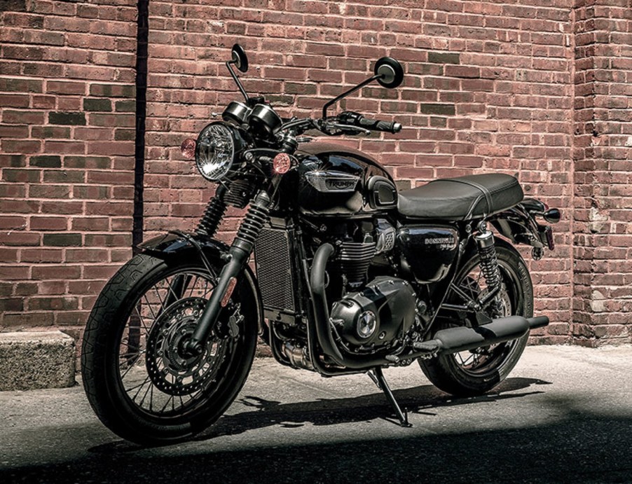 A black 2021 Triumph Bonneville T100 by a brick wall