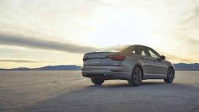 A silver 2021 Volkswagen Jetta parked with the sun in the background